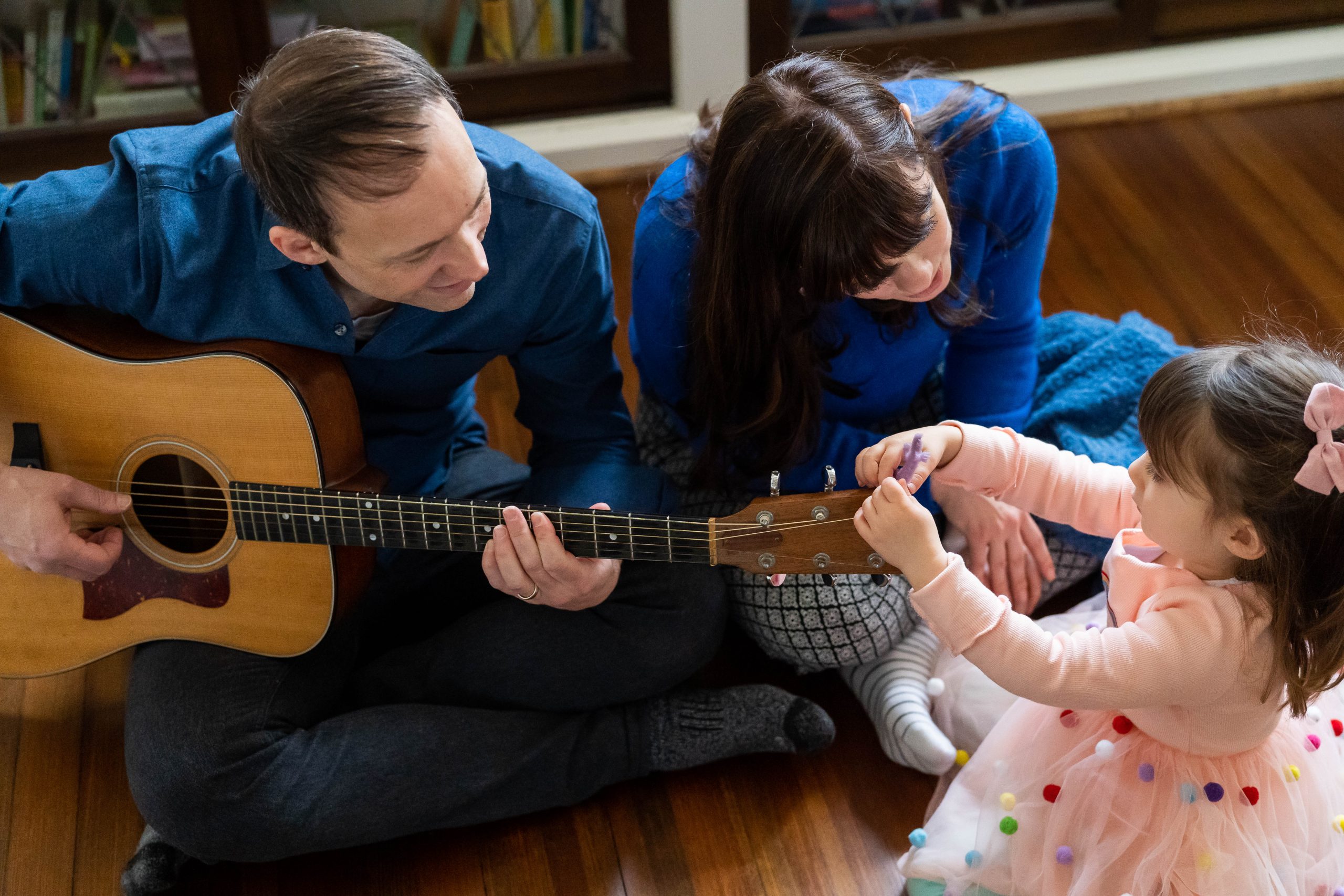 Little girl in tutu playing guitar with parents