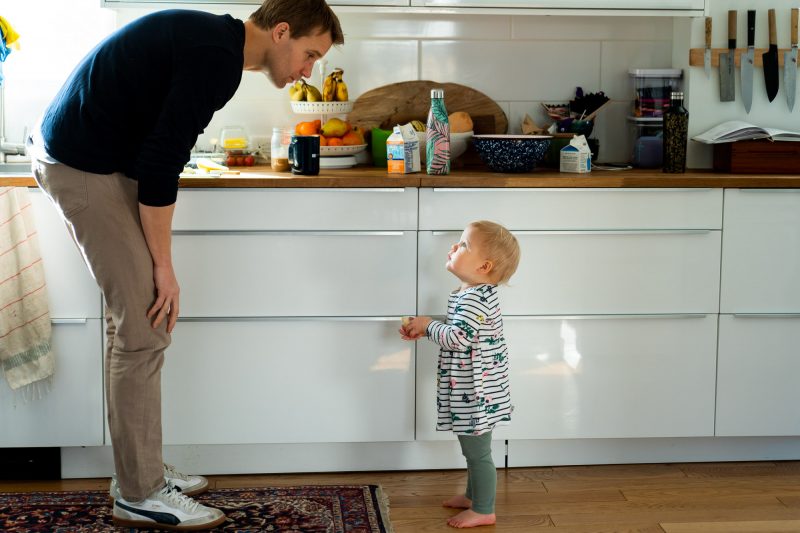 toddler looking up at father in the kitchen