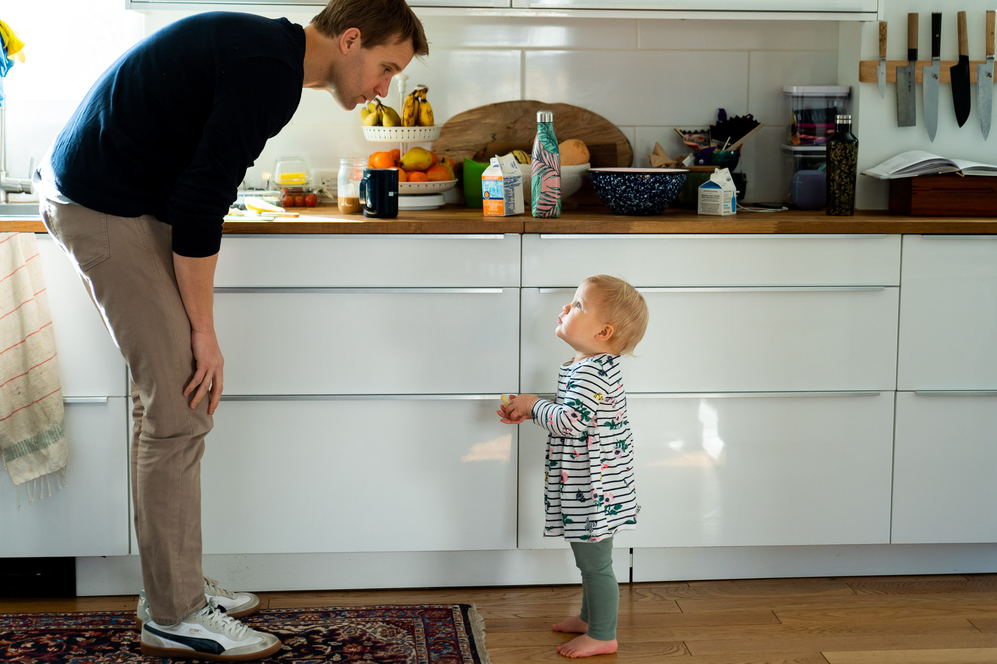 toddler looking up at father in the kitchen getting a snack