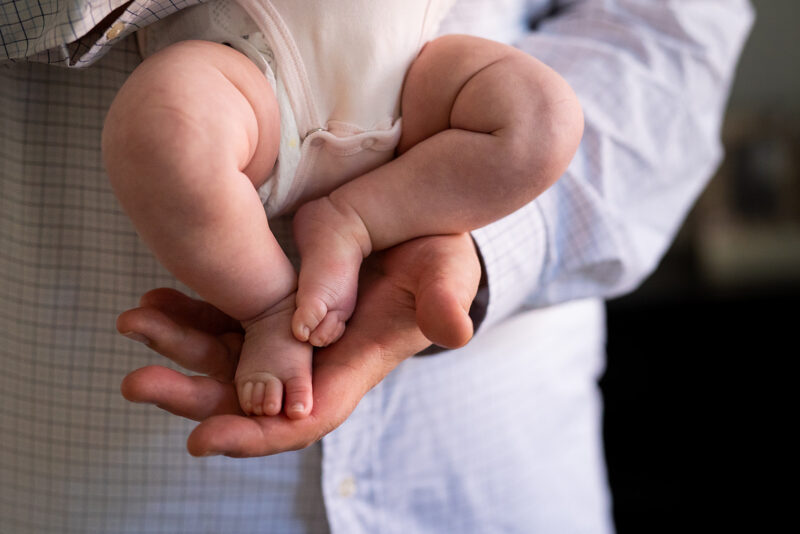 Dad's hands holding chubby newborn feet