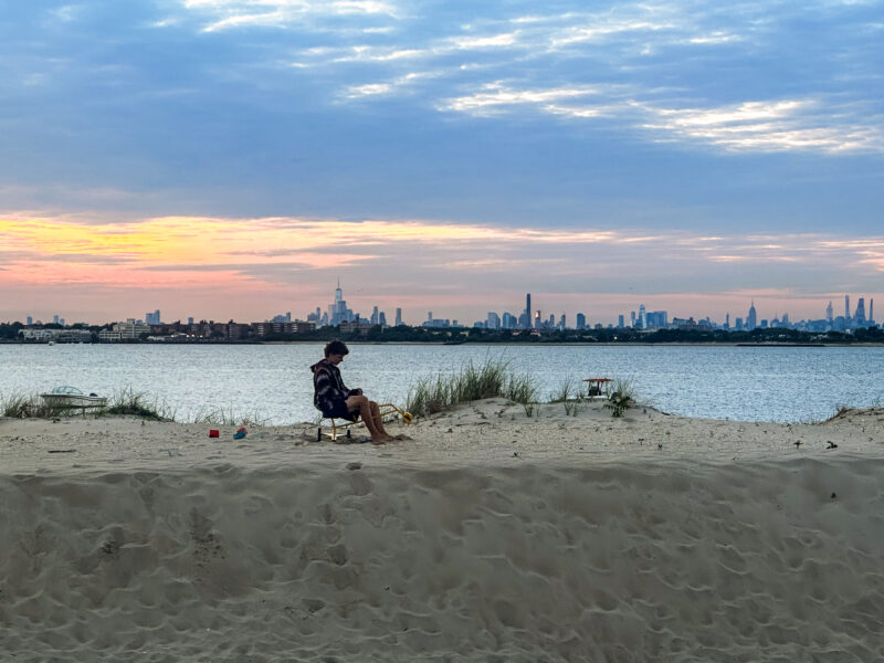 boy sitting on a berm against a sunset skyline