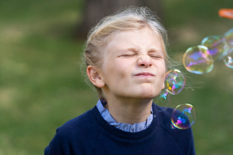 little girl crinkling nose as bubbles touch her face