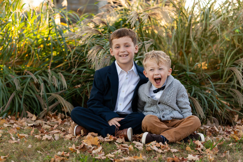 two brothers sitting on the grass together laughing