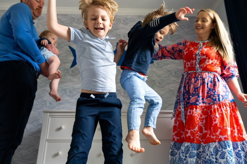 Family smiling and having fun during a in home family photo session with Jaye McLaughlin